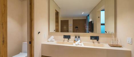 A modern bathroom with a large mirror, a sink, and a toilet.