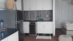 Une cuisine moderne avec des meubles blancs, un lave-vaisselle encastré et un plan de travail doté d’un mixeur.