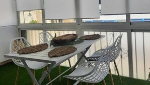 Un espace repas avec une table blanche, des chaises blanches et un luminaire suspendu.