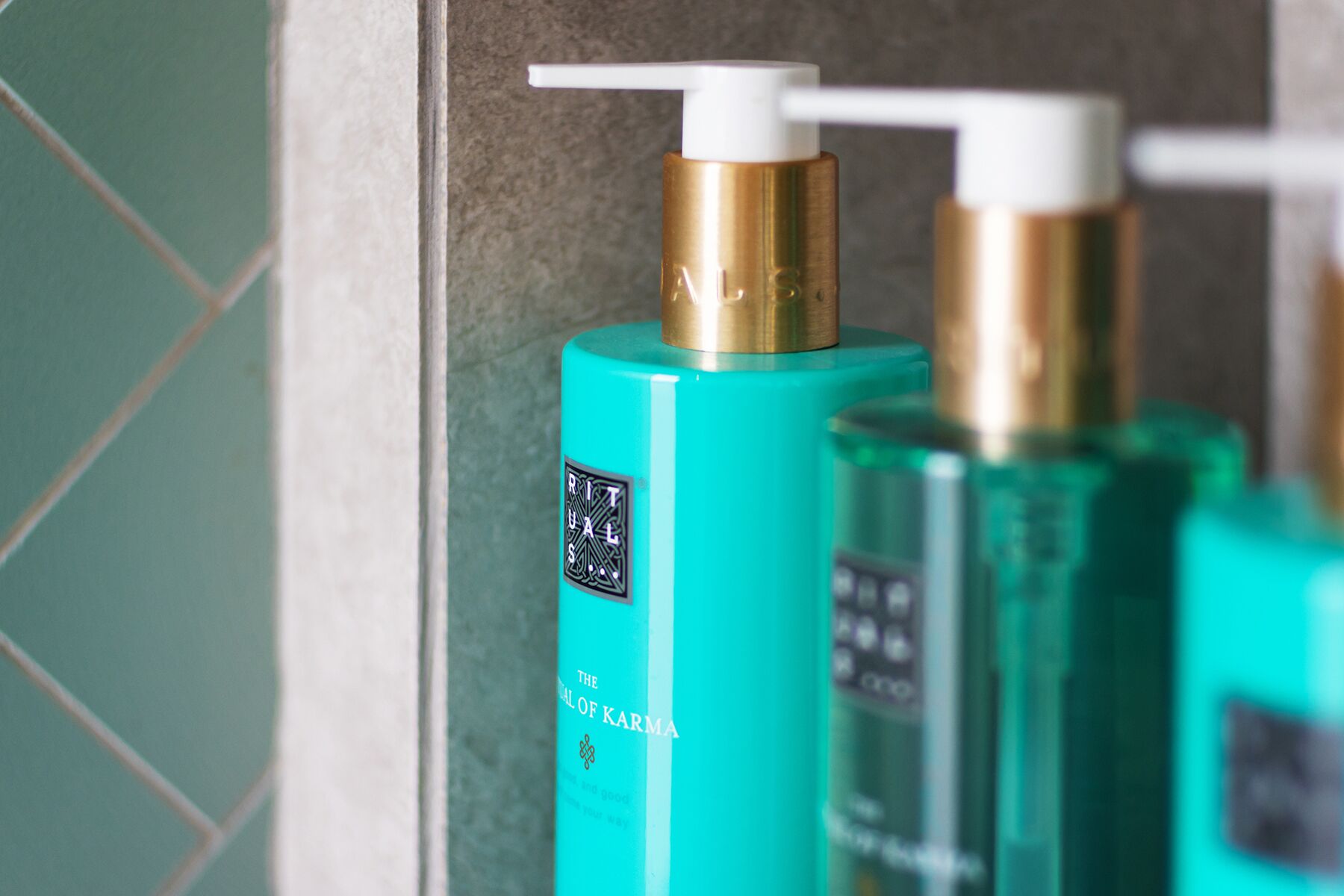 A bathroom with teal-colored bottles of shampoo and conditioner.