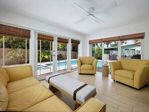 Un vaste espace de vie avec une piscine, des meubles jaunes et de grandes fenêtres.