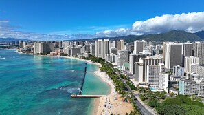 A coastal cityscape with high-rise buildings, a beach, and a clear blue sky.