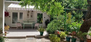 Een terras met een tafel en stoelen, omringd door potplanten en een tuin.