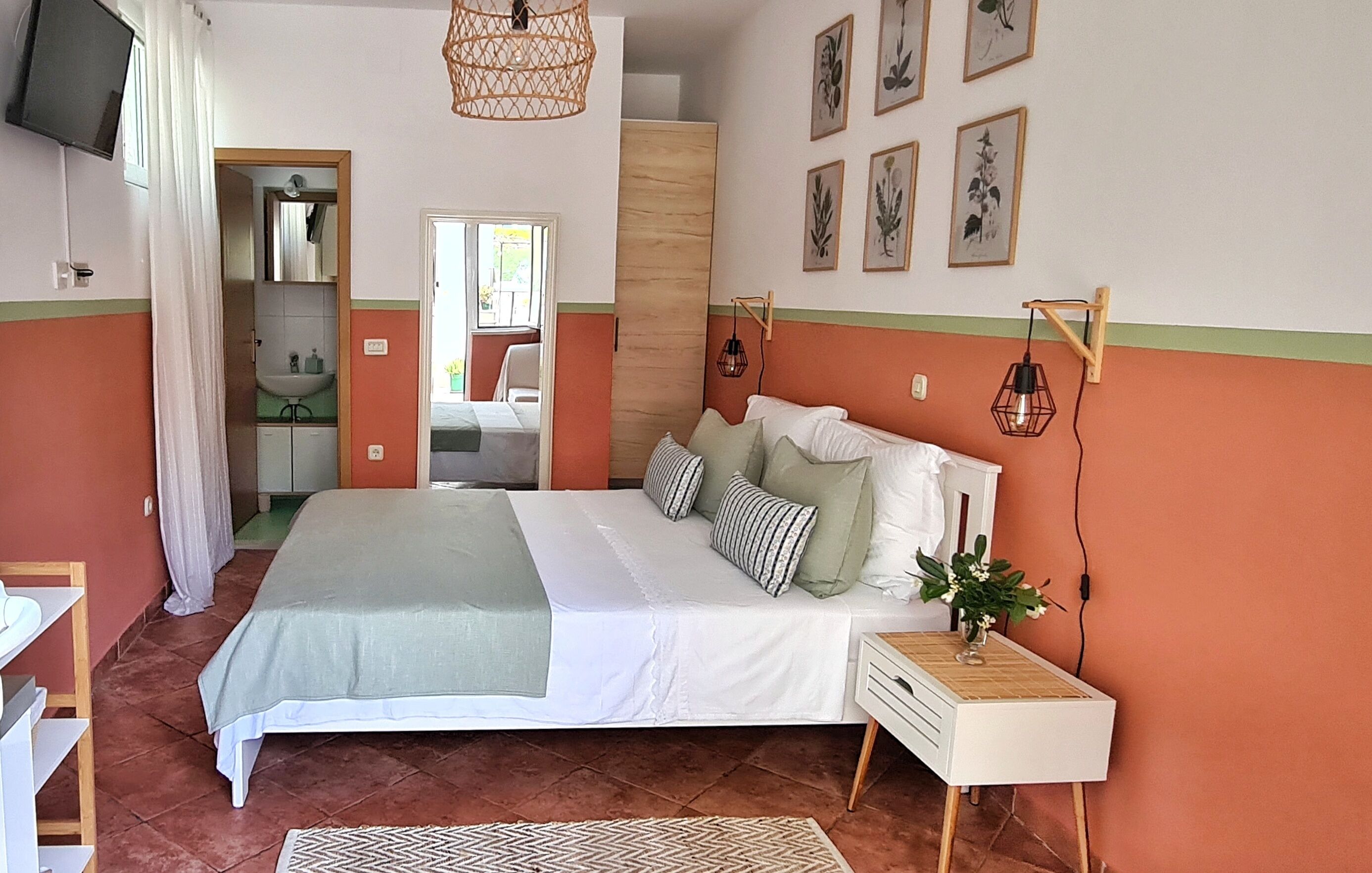 A bedroom with a bed, bedside table, wall-mounted lamp, and framed artwork.