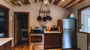 A kitchen with wooden ceiling beams, stainless steel appliances, and a star-shaped light fixture. - Little Blue Cottage - wooded getaway, near beaches and towns (Benton Harbor)