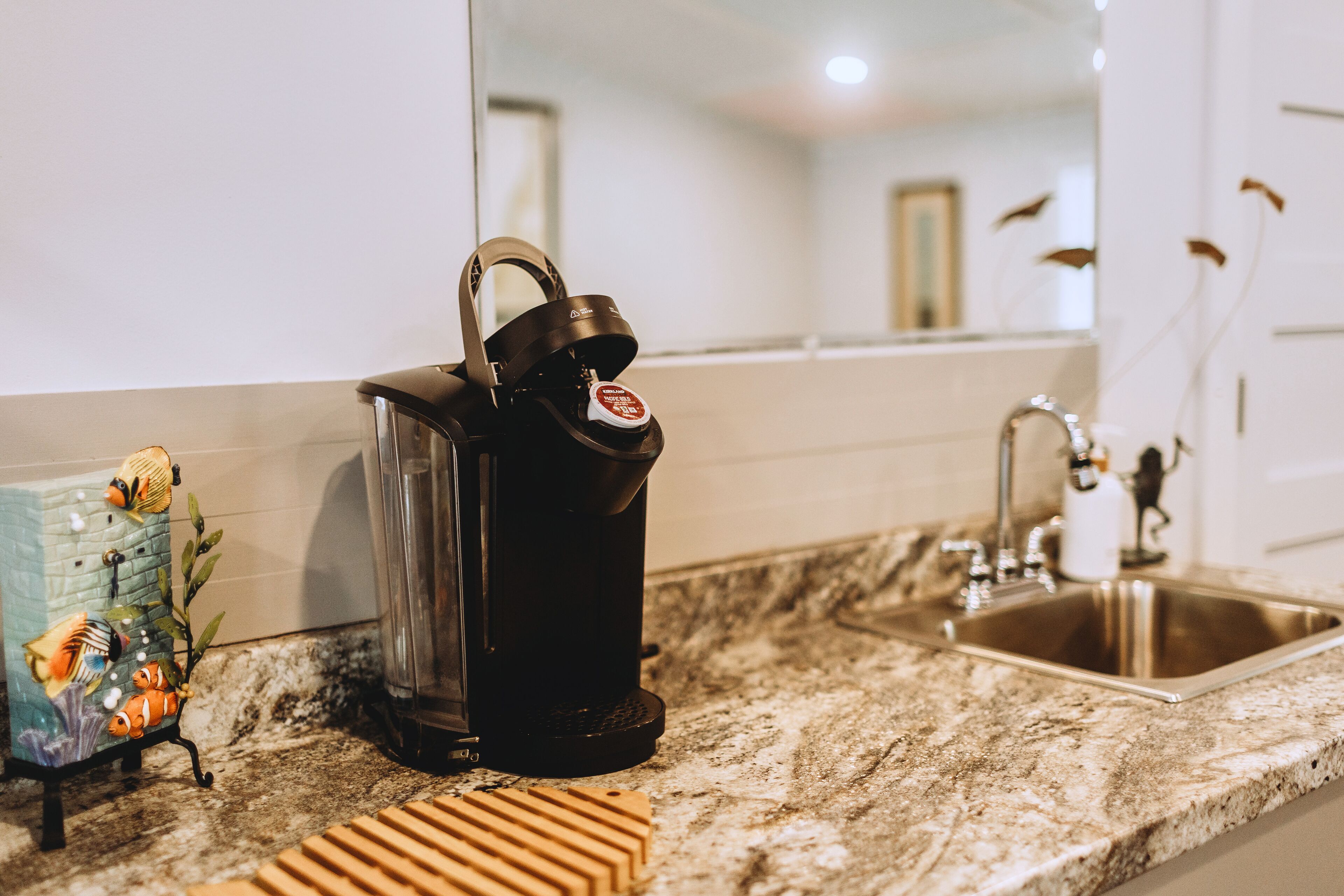 A kitchen counter with a coffee maker, a sink, and a decorative fish tank.
