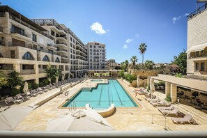 A swimming pool with lounge chairs and a view of multi-story buildings.