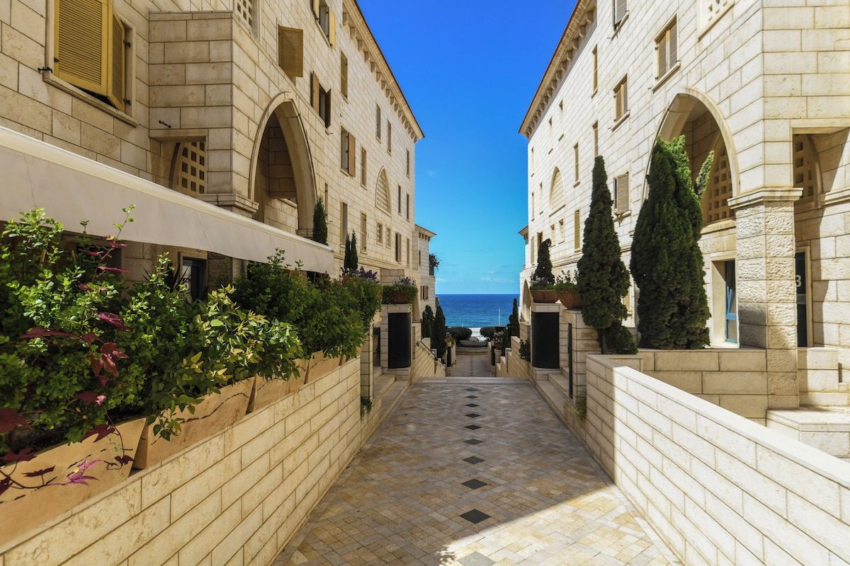 Un sentiero in pietra conduce a un edificio con finestre ad arco e vista sul mare.