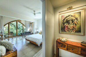 A bedroom with a large window, a bed, a desk, and a chair.
