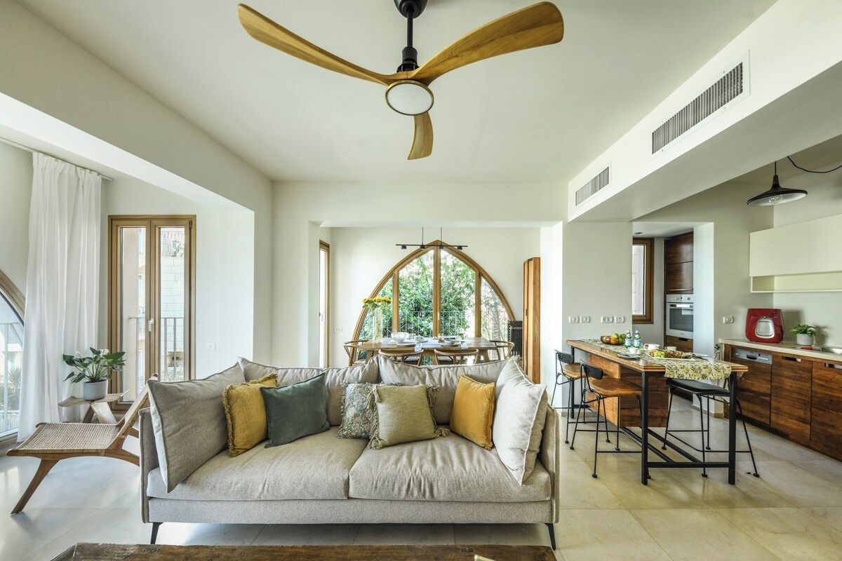 A modern living room with a sofa, a dining table, and a kitchen area.