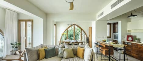 A modern living room with a sofa, a dining table, and a kitchen area.