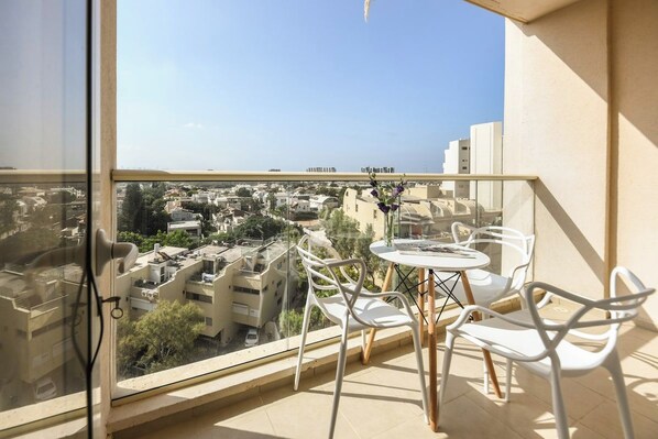 A balcony with a table and chairs, overlooking a cityscape.