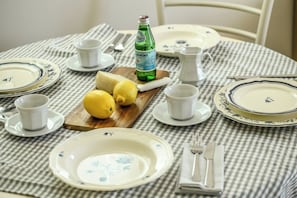 Une table dressée avec des assiettes, des tasses, une bouteille, des citrons et un pichet, ce qui laisse supposer qu’il s’agit d’un décor pour un petit-déjeuner ou une dégustation de thé.
