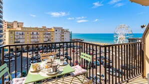A balcony with a table set for breakfast, overlooking a parking lot and a Ferris wheel. - Bedo House - Beachfront Sea View Apartment in Follonica, Follonica, Italy (Follonica)