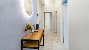 A hallway with a wooden bench, a vase with flowers, and a round mirror on the wall. - Bedo House - Beachfront Sea View Apartment in Follonica, Follonica, Italy (Follonica)