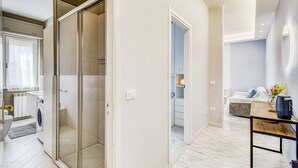 A modern bathroom with a glass shower enclosure, a built-in washing machine, and a toilet. - Bedo House - Beachfront Sea View Apartment in Follonica, Follonica, Italy (Follonica)