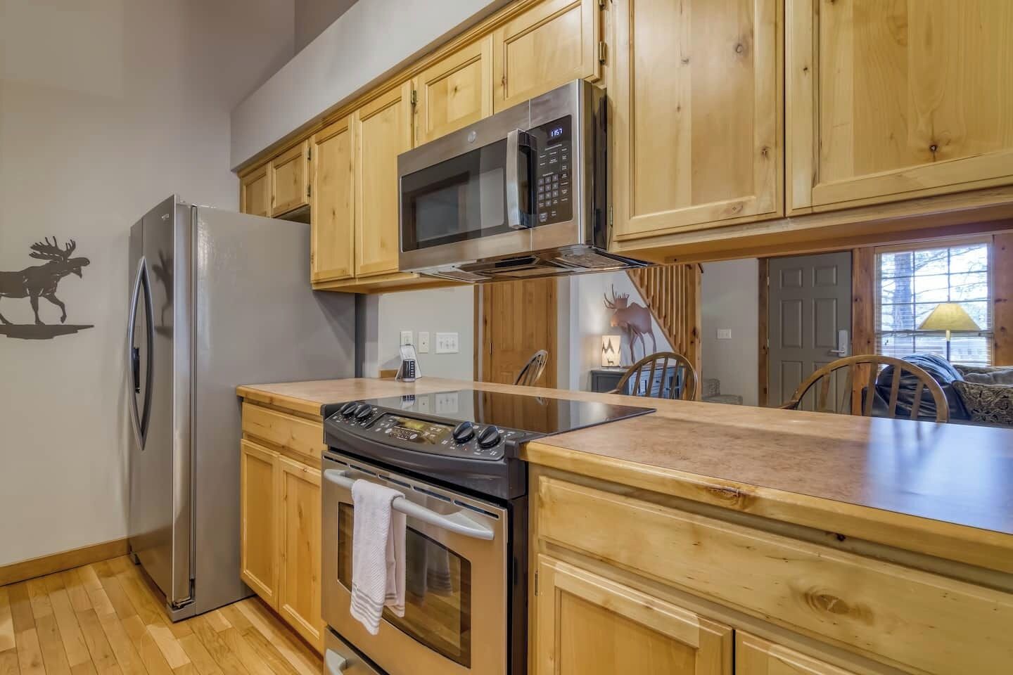 A kitchen with wooden cabinets, a stainless steel refrigerator, a microwave, an oven, and a wooden countertop.