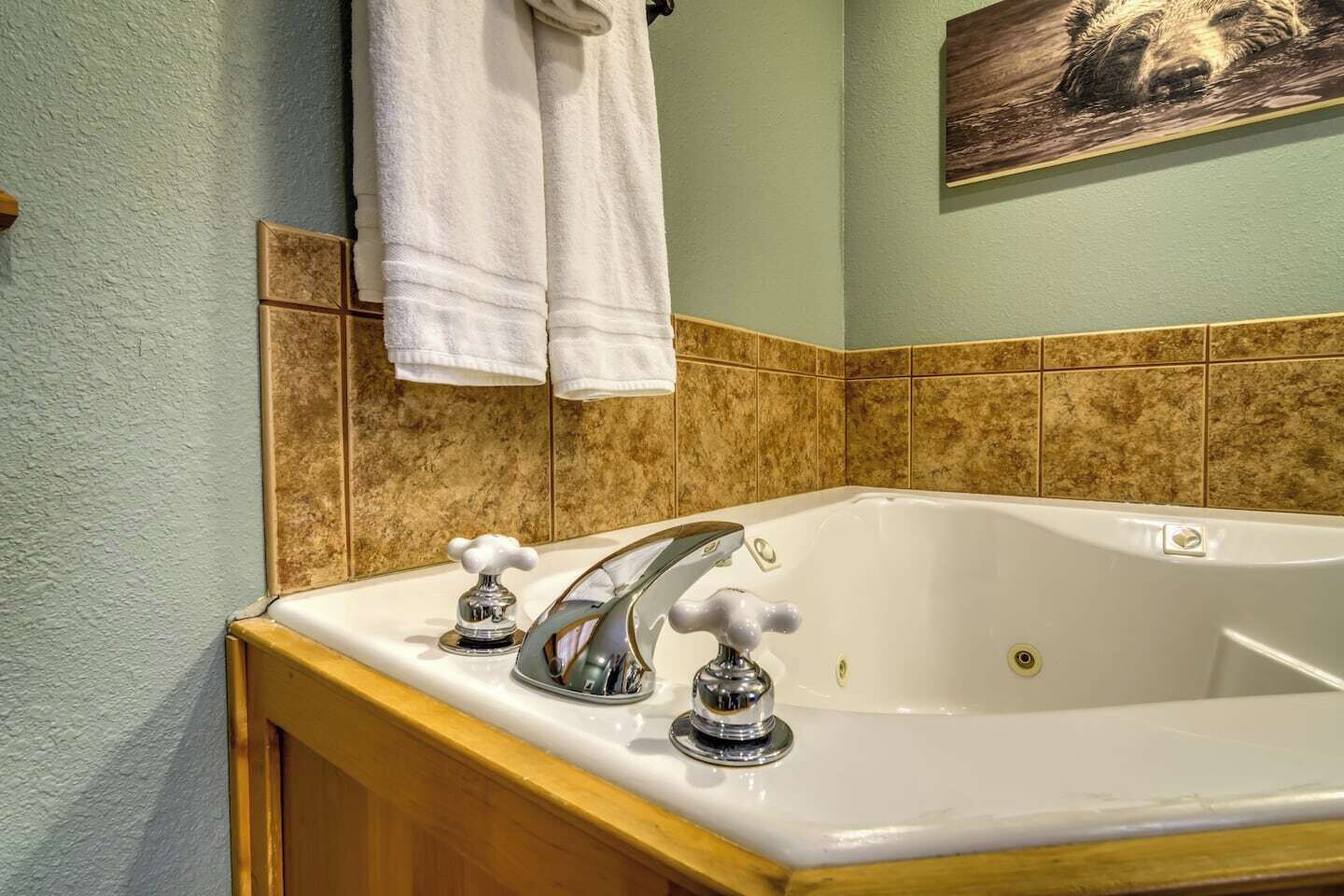 A bathroom with a white bathtub, two chrome faucets, and a wooden cabinet.