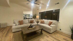 A modern living room with a sectional sofa, a coffee table, and a ceiling fan.