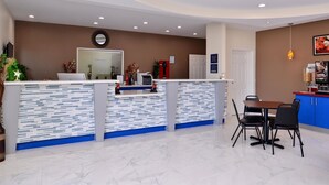 Ein Empfangsbereich im modernen Design mit einer Rezeption, einer Sitzecke mit Tisch und Stühlen sowie einer Theke mit blauen und weißen Fliesen.
