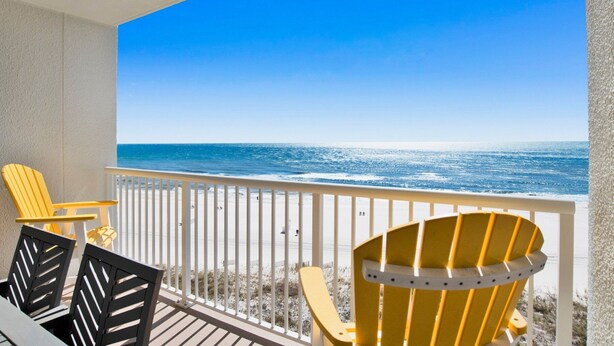 A balcony with a view of the ocean, featuring yellow and black Adirondack chairs and a white railing. - Summer House 705B | Gorgeous Beach Front, Huge Deck, Great Location (Orange Beach)