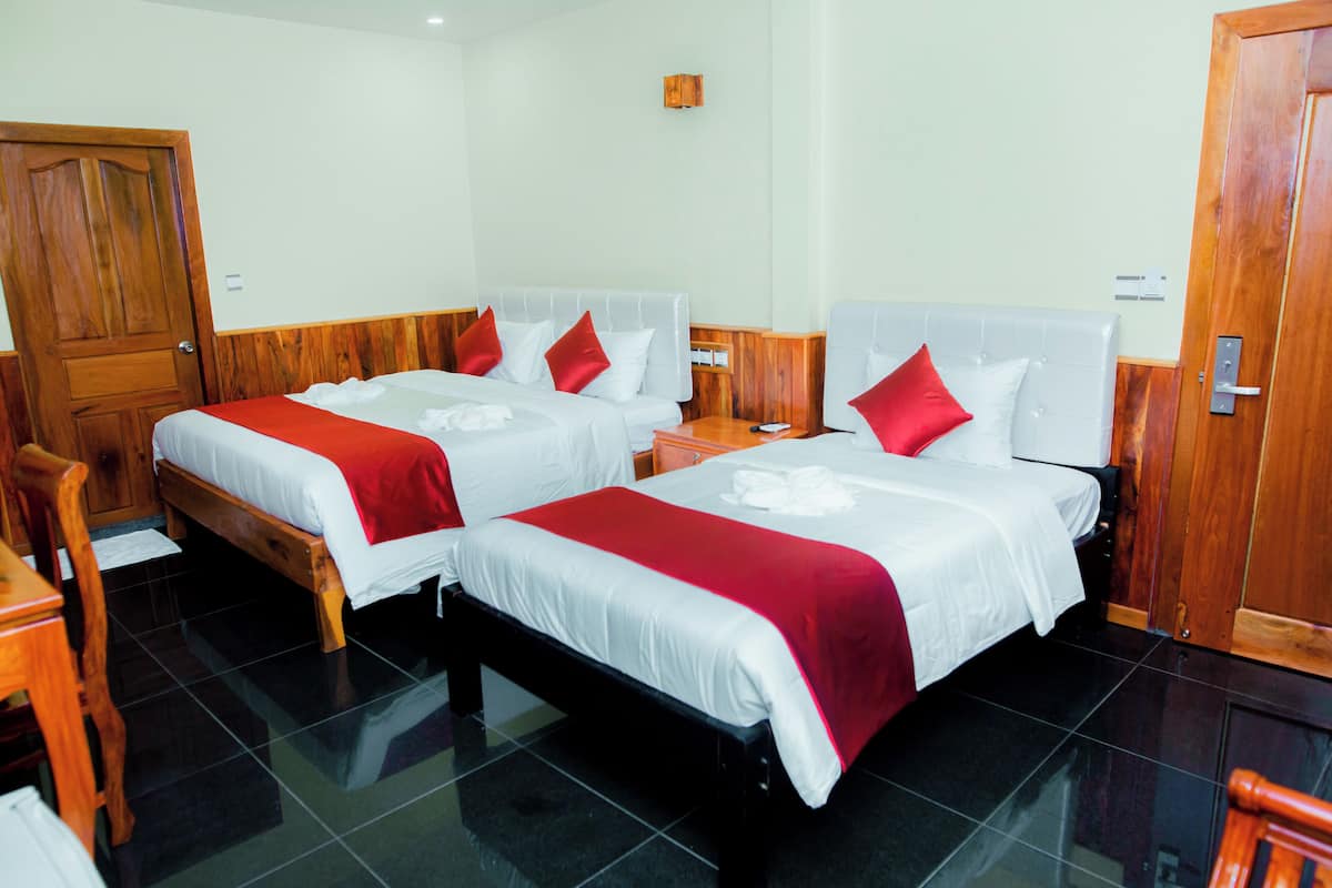 Ein Hotelzimmer mit zwei Betten, Holz-Kopfteilen und einer Holztür.