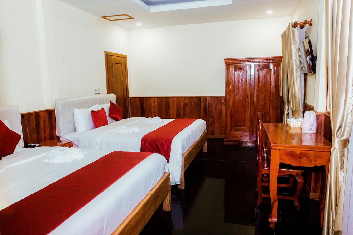 Ein Hotelzimmer mit zwei Betten, einem Holztisch, einem Spiegel und einem Schrank aus Holz.