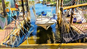 Un bateau était amarré dans une voie navigable étroite, entouré de structures en bois, et des cordes et des filets étaient visibles.