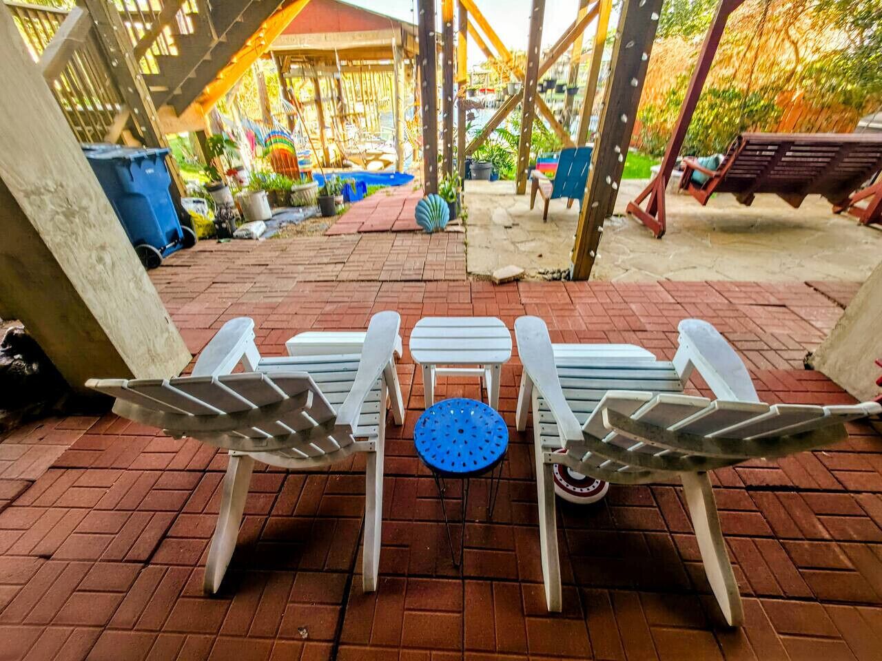 Un espace patio comprenant une table et quatre chaises, une balançoire et un coin salon abrité.