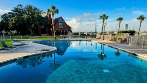 Une piscine aux eaux cristallines, des chaises longues, un panneau indiquant « INTERDIT DE PLONGER » et, au fond, le bâtiment de l’hôtel.