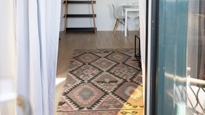Une pièce avec un tapis à motifs, une échelle, une table blanche et un tableau accroché au mur.