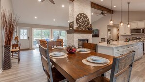 Une cuisine spacieuse avec un grand îlot central, des chaises en bois et une table à manger pour quatre personnes.