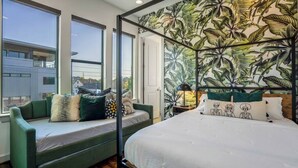 A bedroom with a bed, a sofa, and a window. - Urban Jungle Retreat in the HTX Skyline (Houston)
