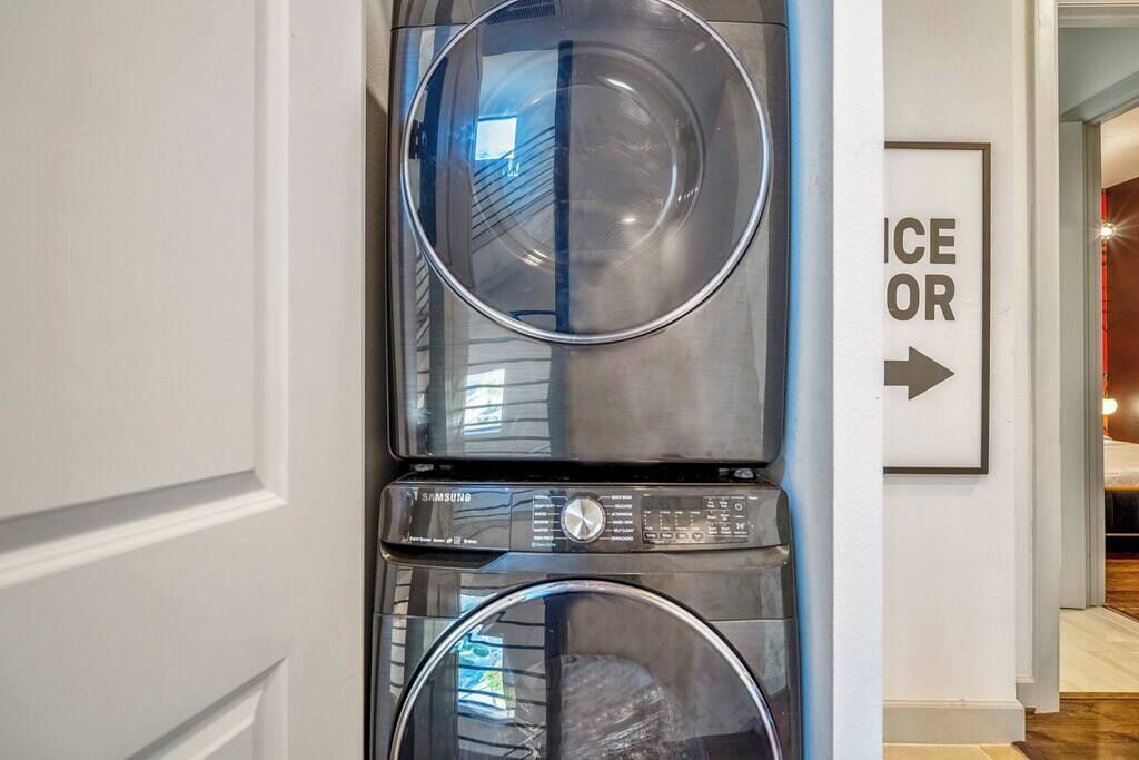 A stacked washer and dryer unit in a hallway with a sign indicating the direction to the ice or water.