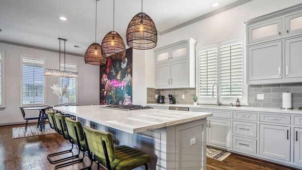 A modern kitchen with white cabinets, a large island, and pendant lighting. - Urban Jungle Retreat in the HTX Skyline (Houston)
