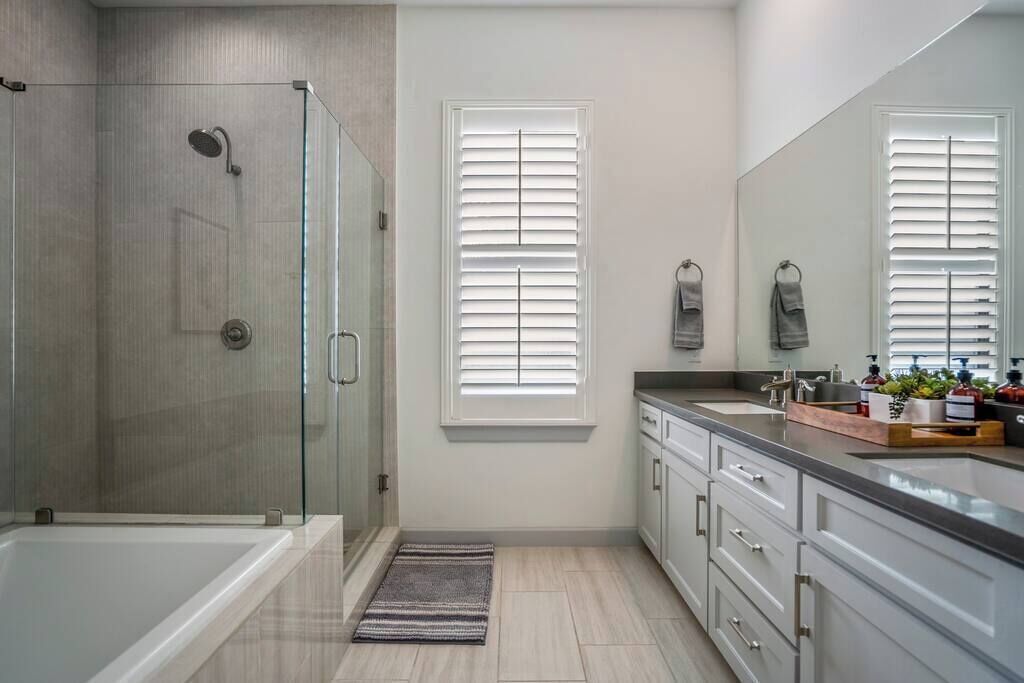 A modern bathroom with a glass-enclosed shower, a large mirror, and a vanity with a sink and countertop.