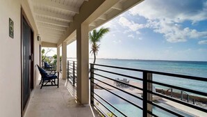 Un balcon avec vue sur l’océan, un palmier et du mobilier d’extérieur.