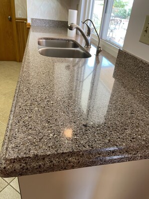 A kitchen with granite countertops, stainless steel sink, and a window providing natural light.