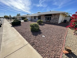 Una casa residencial con fachada de piedra, un porche delantero y un camino de entrada de grava.