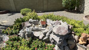 A garden with rocks, a birdhouse, and a statue of a bear. - 5 star resort pool,jet tub, out Drshower,barbeque,fire pit,tvs,stunning backyard (Sun City)