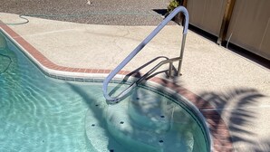 A swimming pool with clear water, a brick edge, and a metal handrail. - 5 star resort pool,jet tub, out Drshower,barbeque,fire pit,tvs,stunning backyard (Sun City)