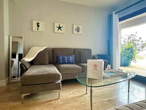 A modern living room with a sectional sofa, a glass coffee table, and wall art.