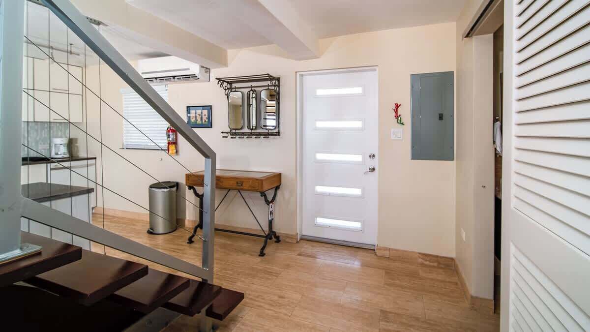 A hallway with a wooden bench, a white door, and a mirror on the wall.