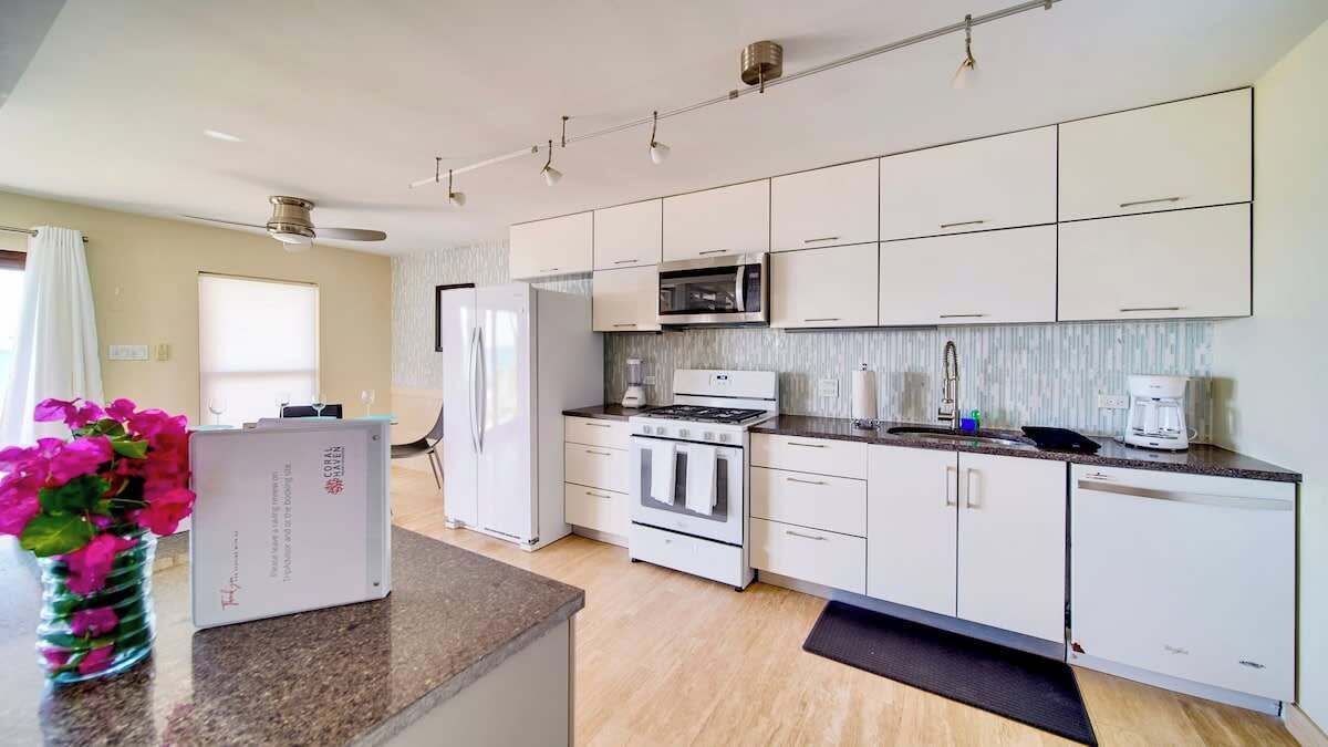 A modern kitchen with white cabinets, a microwave, stove, and a refrigerator.