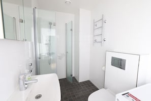 A modern bathroom with a glass-enclosed shower, a white sink, and a toilet. - 2ndhomes Bright 1BR Home in Kamppi (Helsinki)