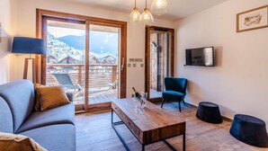 Ein modernes Wohnzimmer mit einer Couch, einem Holztisch und einem an der Wand befestigten Fernseher.