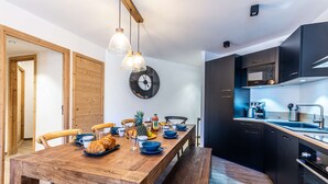 Eine moderne Küche mit dunklen Schränken, einem Holztisch und einer Uhr an der Wand.