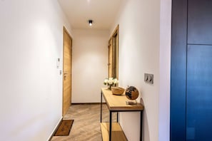 Un pasillo con puertas de madera, una mesita con un globo terráqueo y flores, y una pared azul.