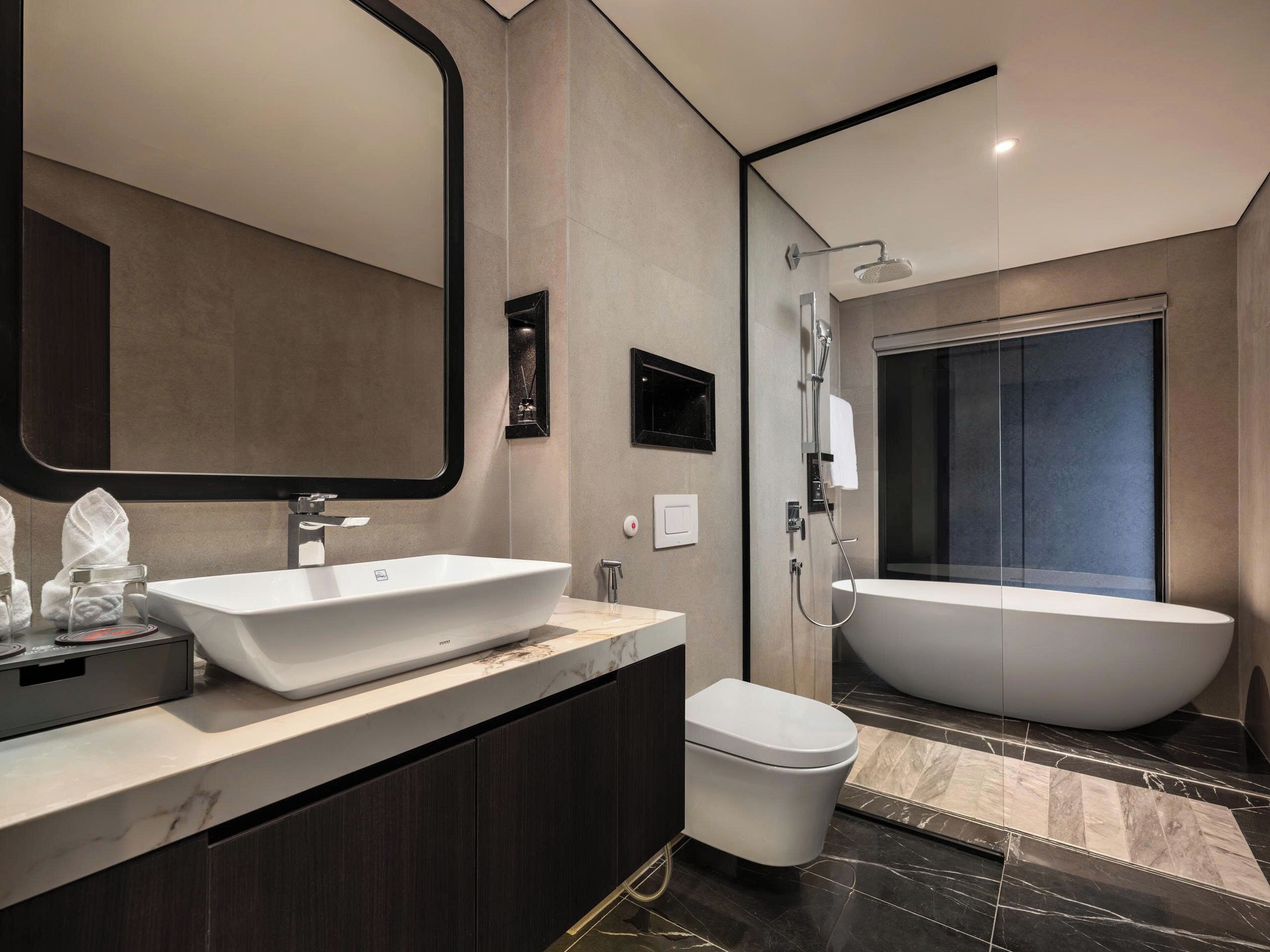 Un baño moderno con una bañera independiente grande, un lavabo instalado en la pared y un inodoro.