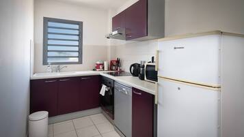 Een koelkast, een oven, kookgerei, borden en bestek